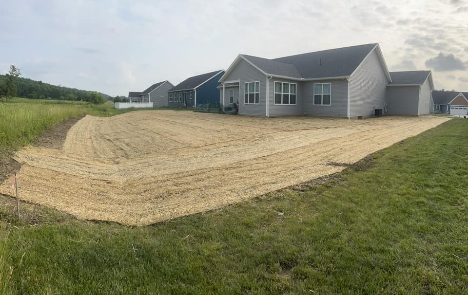 Newly prepared lawn area with straw covering behind modern homes in a suburban setting.