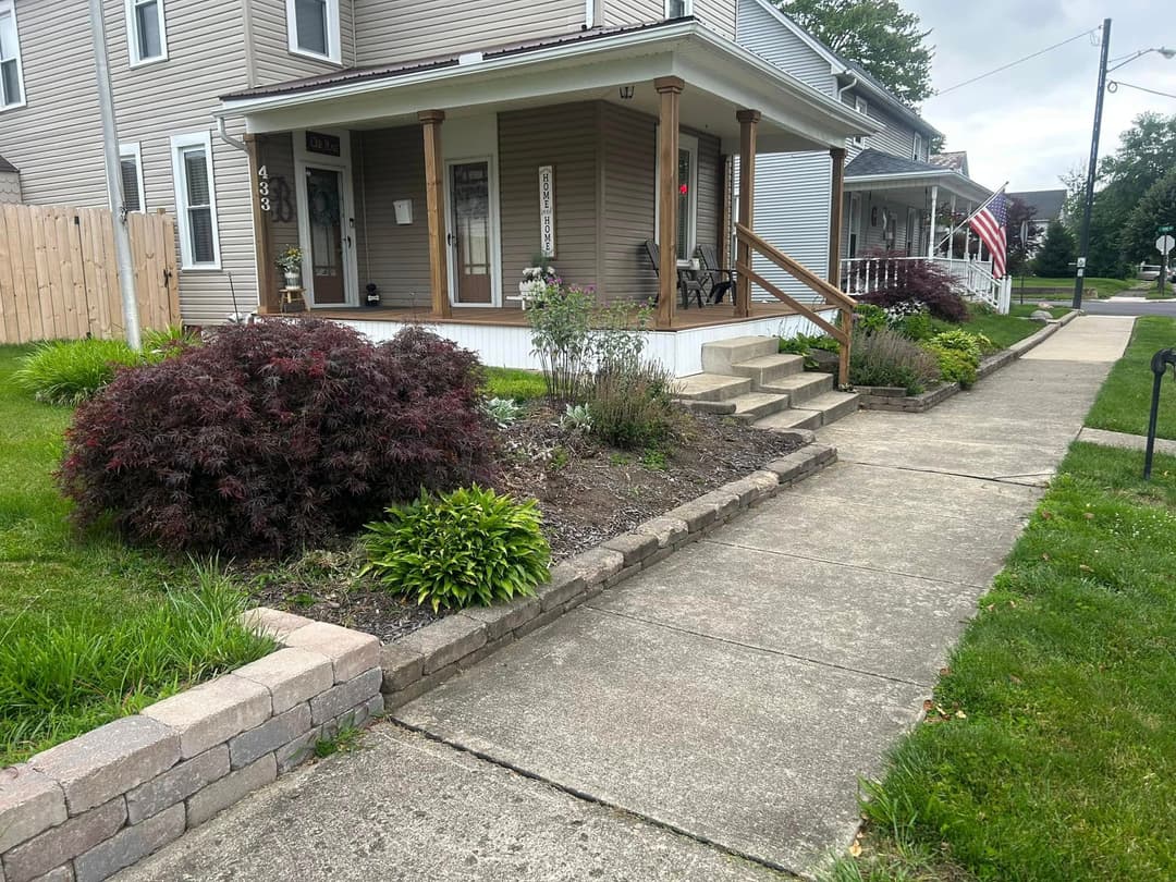 Residential home exterior with landscaped garden, sidewalk, and porch steps.