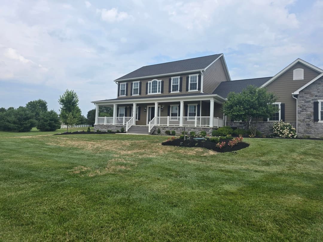 Beautiful two-story house with a porch, landscaped yard, and scenic surroundings.