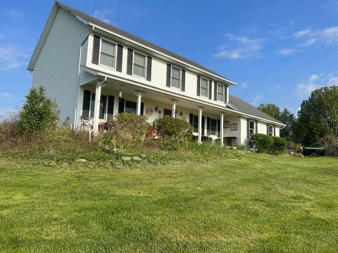 Two-story white house with a green lawn and clear blue sky in the background.