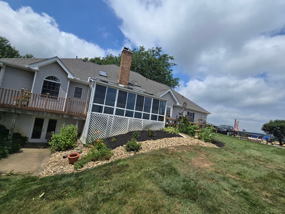 Modern home exterior with a screened porch, landscaped yard, and cloudy sky in the background.