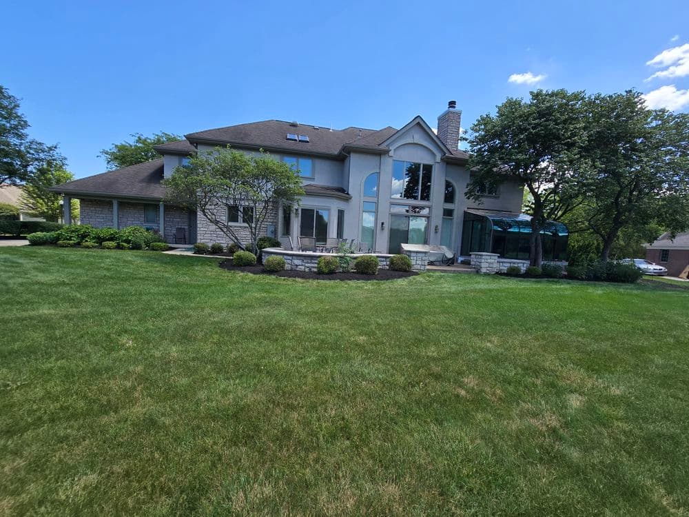 Elegant two-story suburban home with large windows and lush green lawn under a clear blue sky.