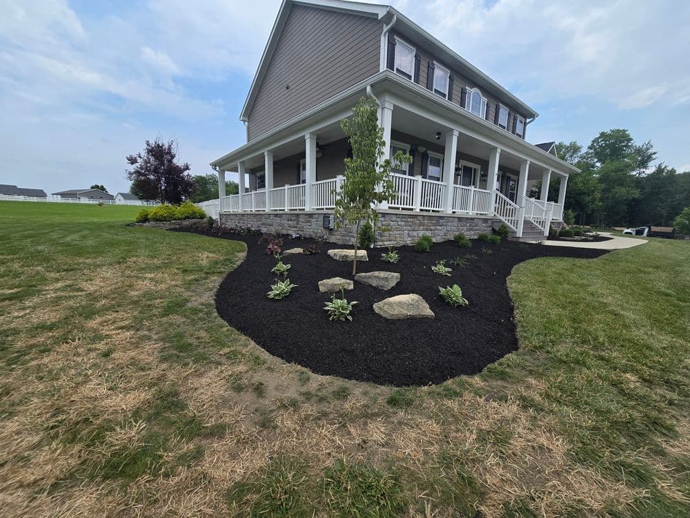 Beautifully landscaped home exterior featuring mulch beds, plants, and a welcoming porch.
