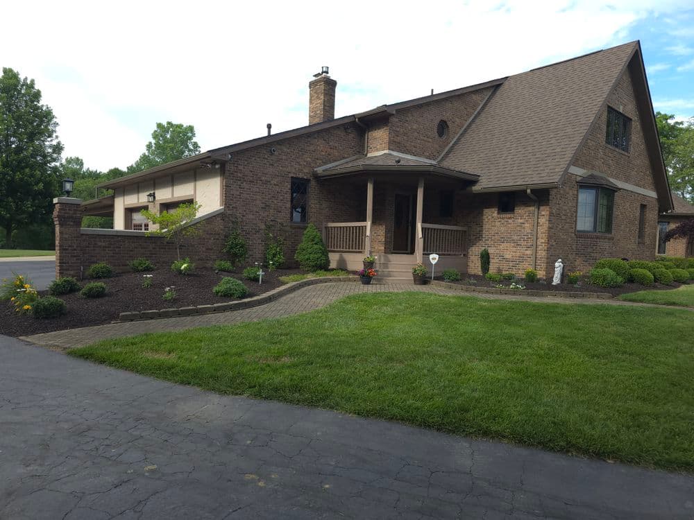 Beautiful brick house with landscaped garden, driveway, and welcoming front porch.
