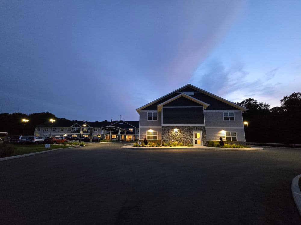 Modern residential building at dusk with exterior lighting and landscaped surroundings.
