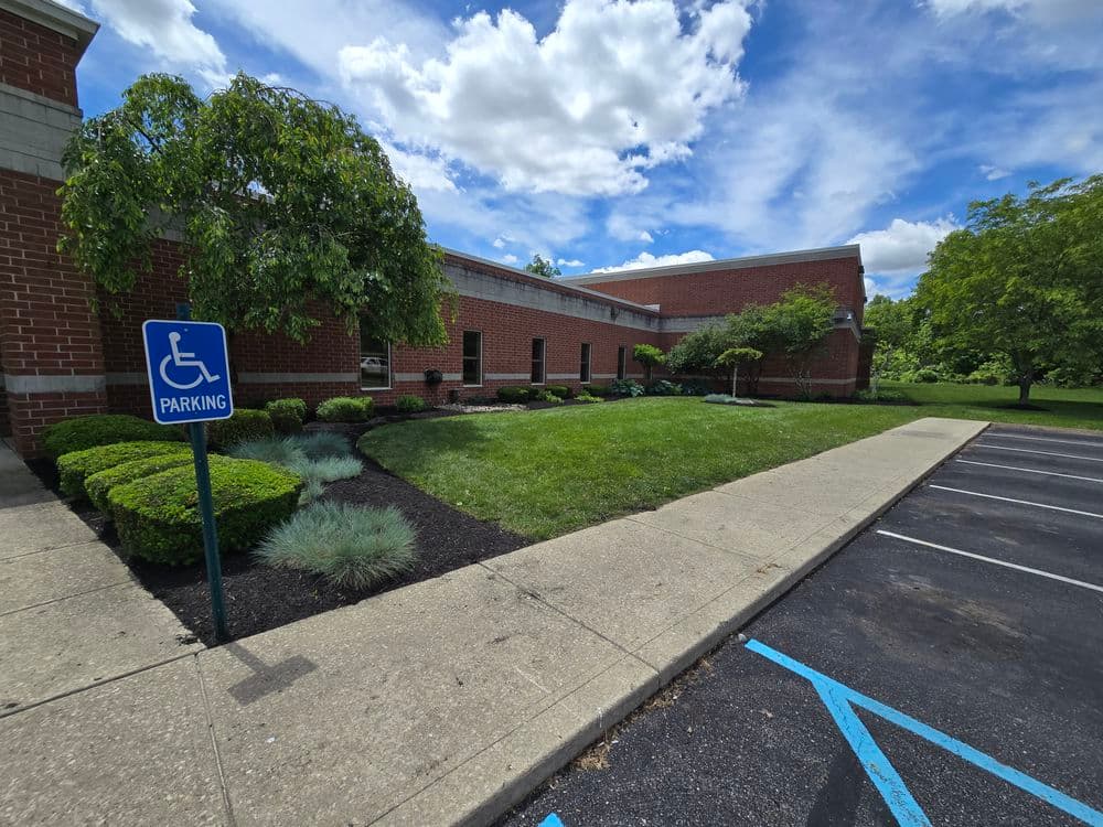 Accessible parking area next to a landscaped building with blue skies and clouds.