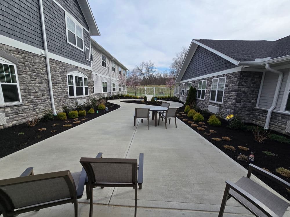 Outdoor patio area with seating, landscaped gardens, and modern building architecture.