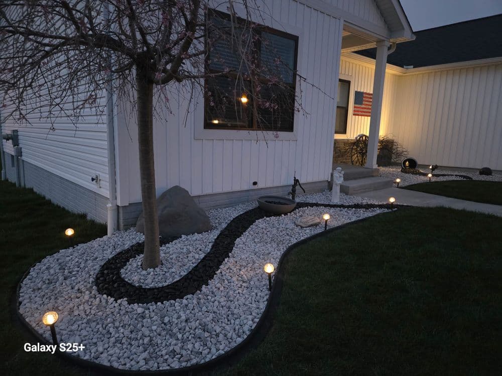 Elegant front yard landscaping with path, decorative stones, tree, and soft lighting at dusk.